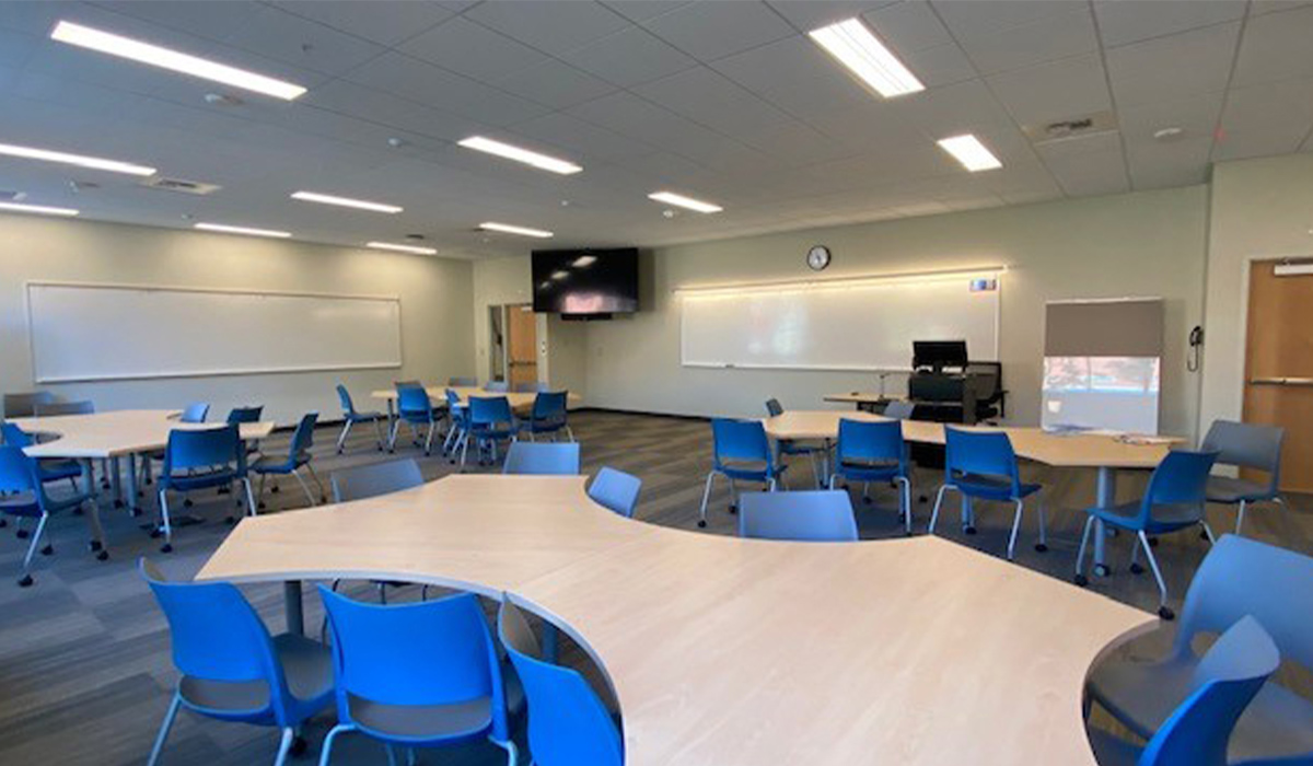A classroom in Mish ee twie with blue chairs and irregularly shaped tables.