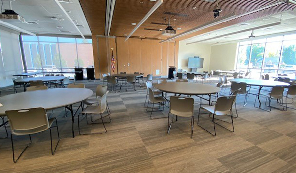 A conference center in Mish ee twie with round tables, chairs, and a presentation screen.