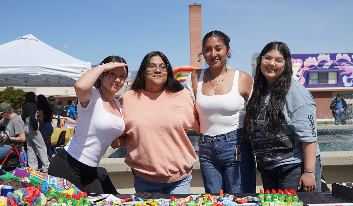 Three young woman in front of table by WVC fountain.