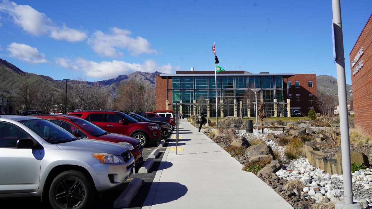 Cars parked in visitor spots at Wenatchee Campus with sunny skies