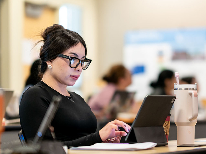 Female student with glasses in class with computer.