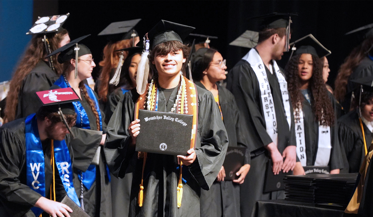 Photo of an Omak graduate holding up diploma at the 2026 graduation ceremony.