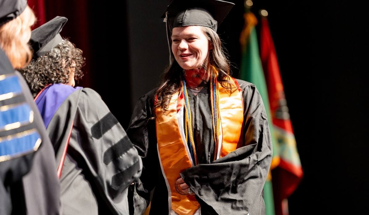 WVC Omak graduate on stage receiving diploma from Trustee
