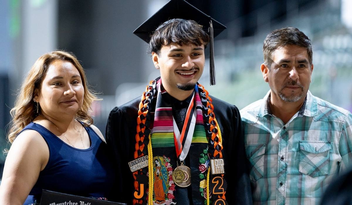 WVC graduate at ceremony with a family member on each side