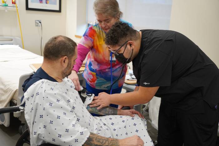Photo of CNA instructor assisting two students learning skills