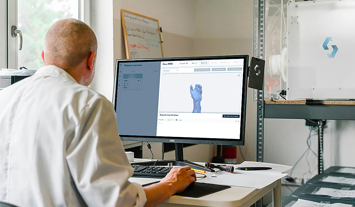 A designer sits at a computer and works on a design of a hand.