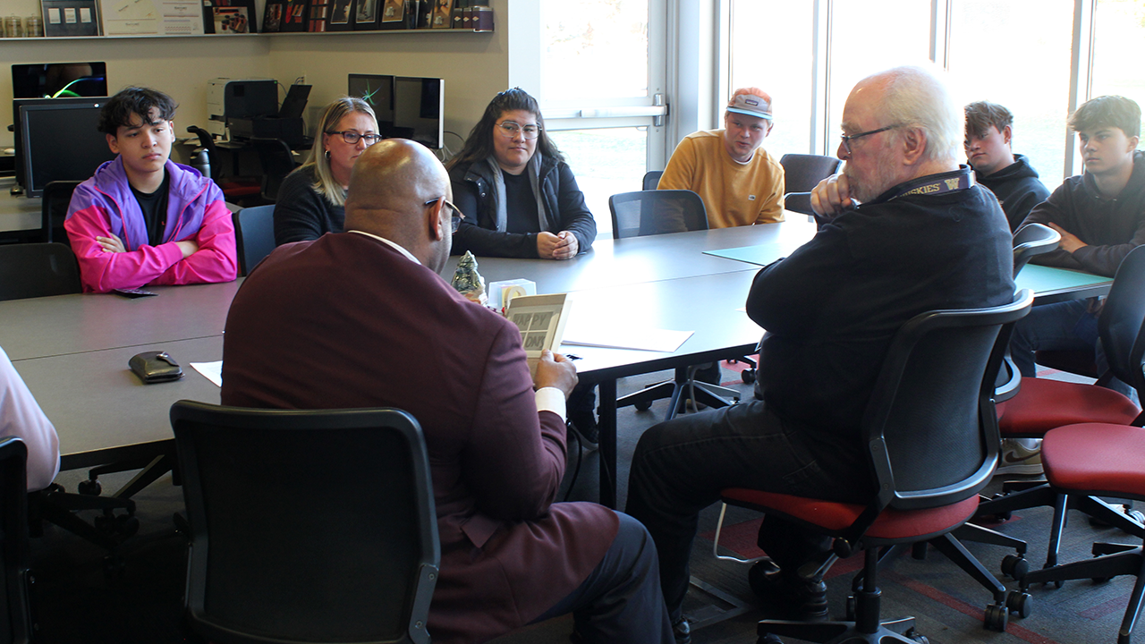 The college president studies a holiday card that a graphic design student has shared with him.