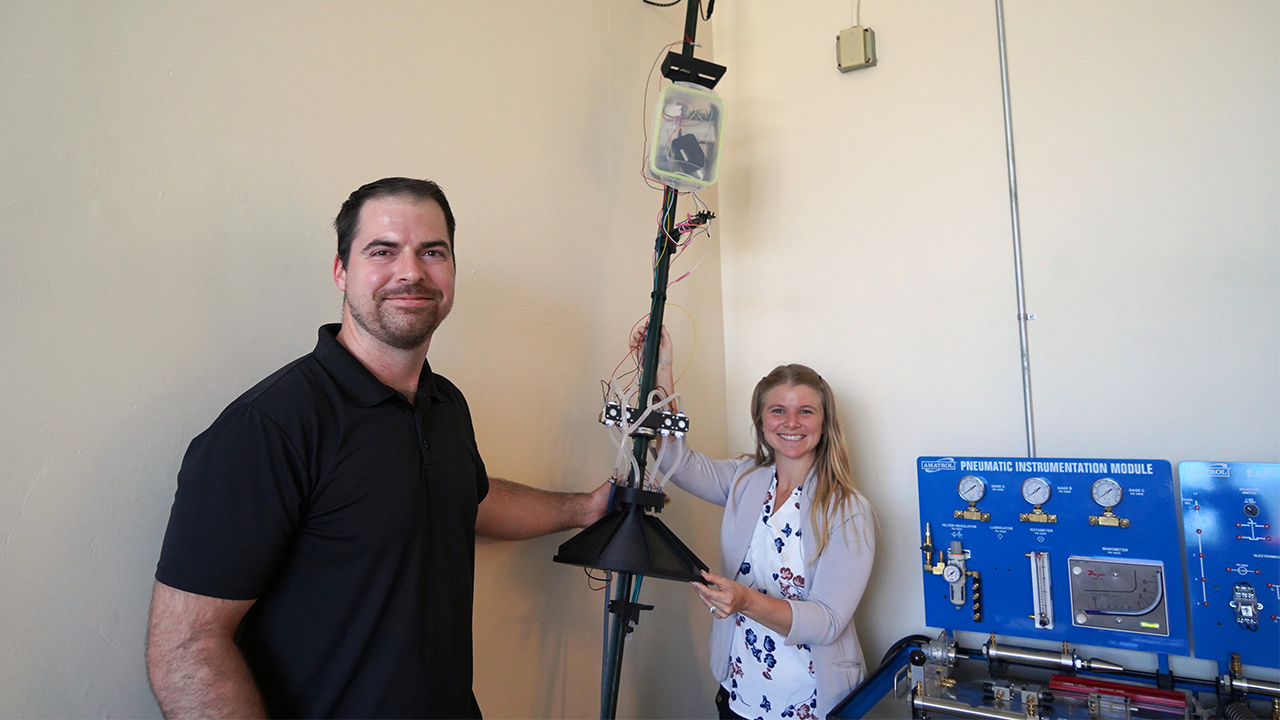 Two WVC Engineering students hold up a pesticide sensor that they created as their capstone project.