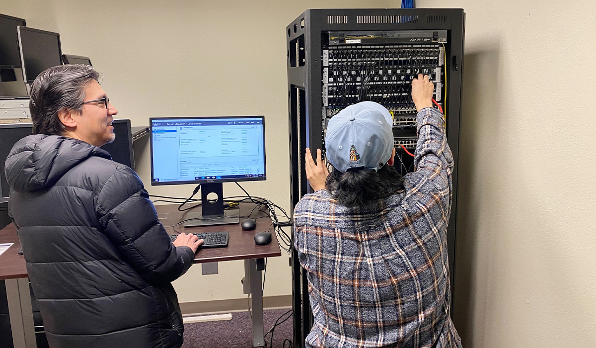 Two people work on a computer system.
