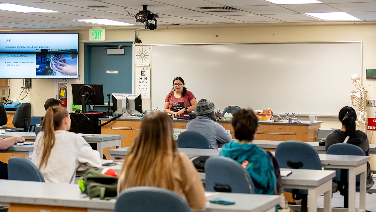 A WVC Omak science professor stands at the front of a lab, with students seated at long tables.
