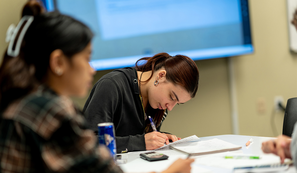 A student sits at a table and completes an assignment.