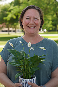 Portrait of Julie Smith standing outside and holding a potted plant