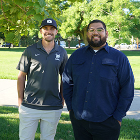 Aaron Vaughn and Levi Vega stand side by side beneath the branches of a tree.