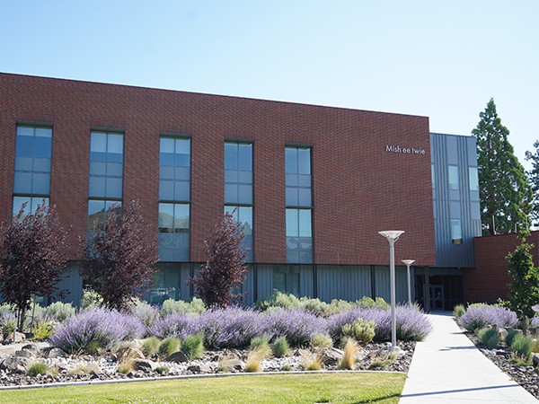 Exterior photo of the Mish ee twie building surrounded by purple sage and saplings