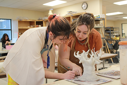 Professor Sarah Sprouse works with a student on her ceramics project.