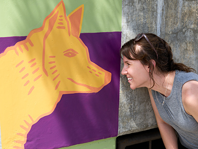 Ellen Bruex stands nose to nose with a dog mural she created.