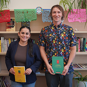 Professor Saxon Spillman and Dr. Maria Morales-Sanchez hold up books with a bookshelf behind them.